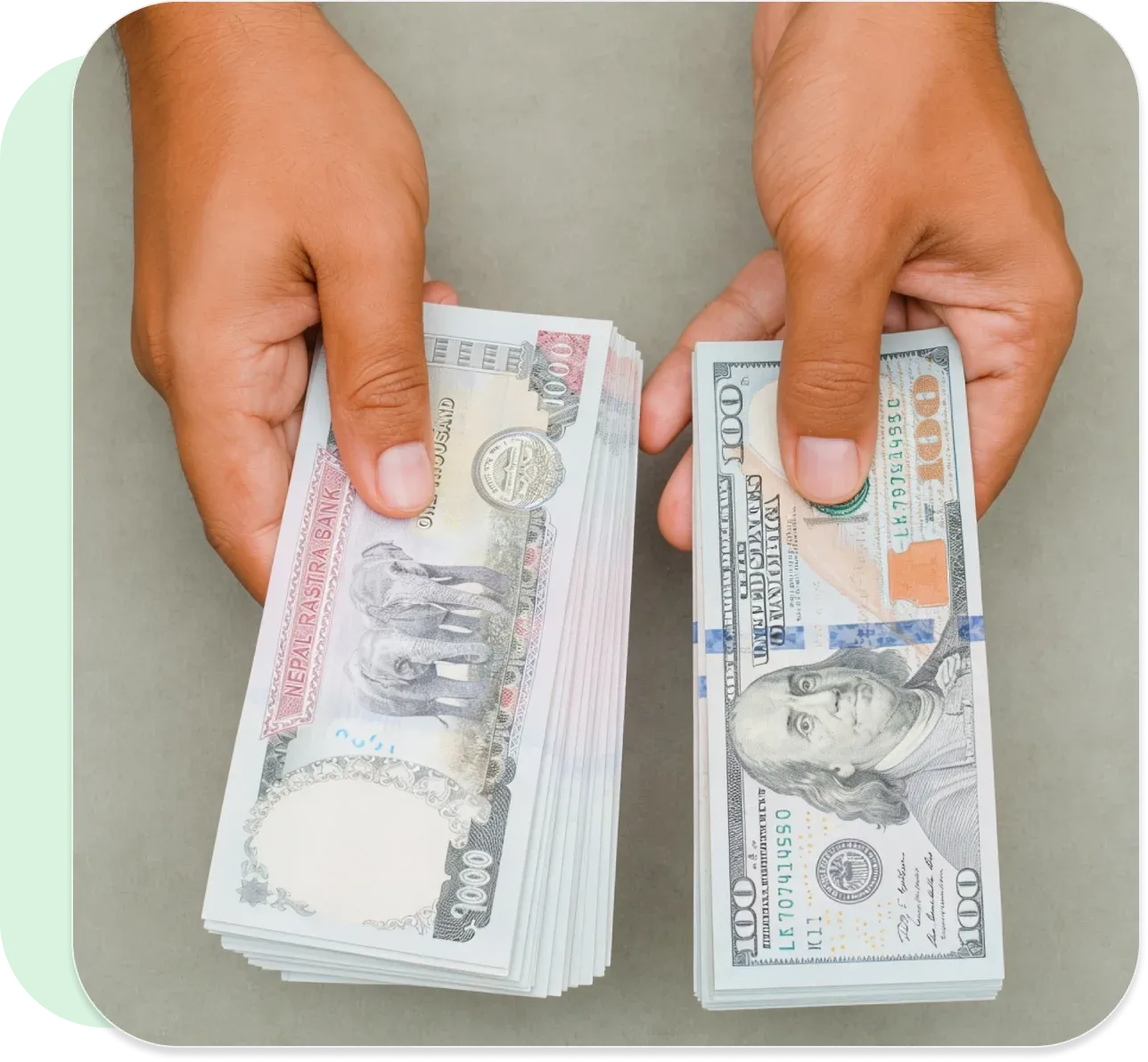 Hands holding stacks of Nepali rupees and U.S. dollars